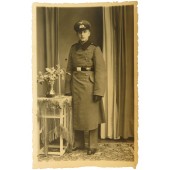 Foto van een Duitse pionierssoldaat ten voeten uit, in een overjas en een vizierpet